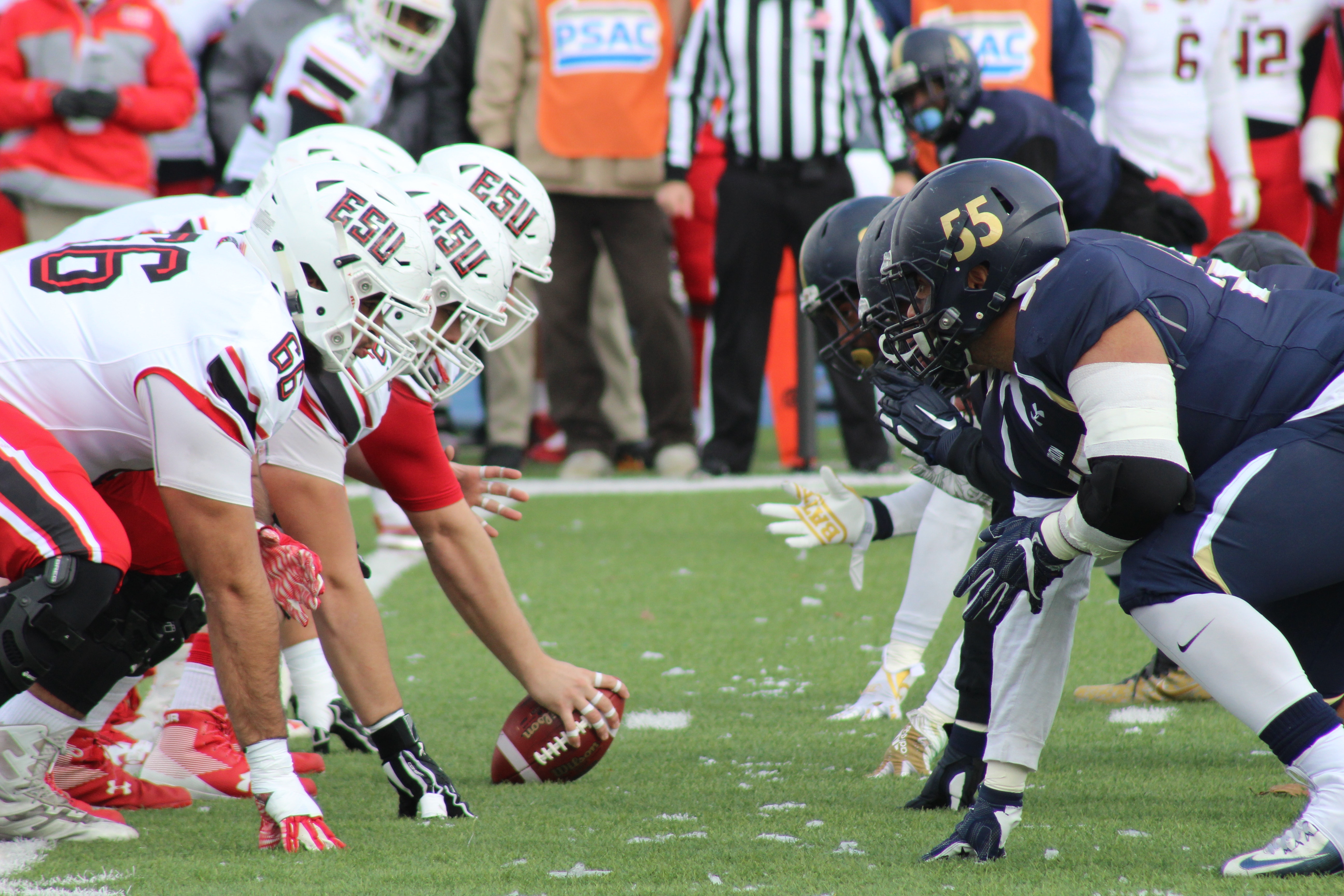American football offensive line players in helmets at the line of scrimmage