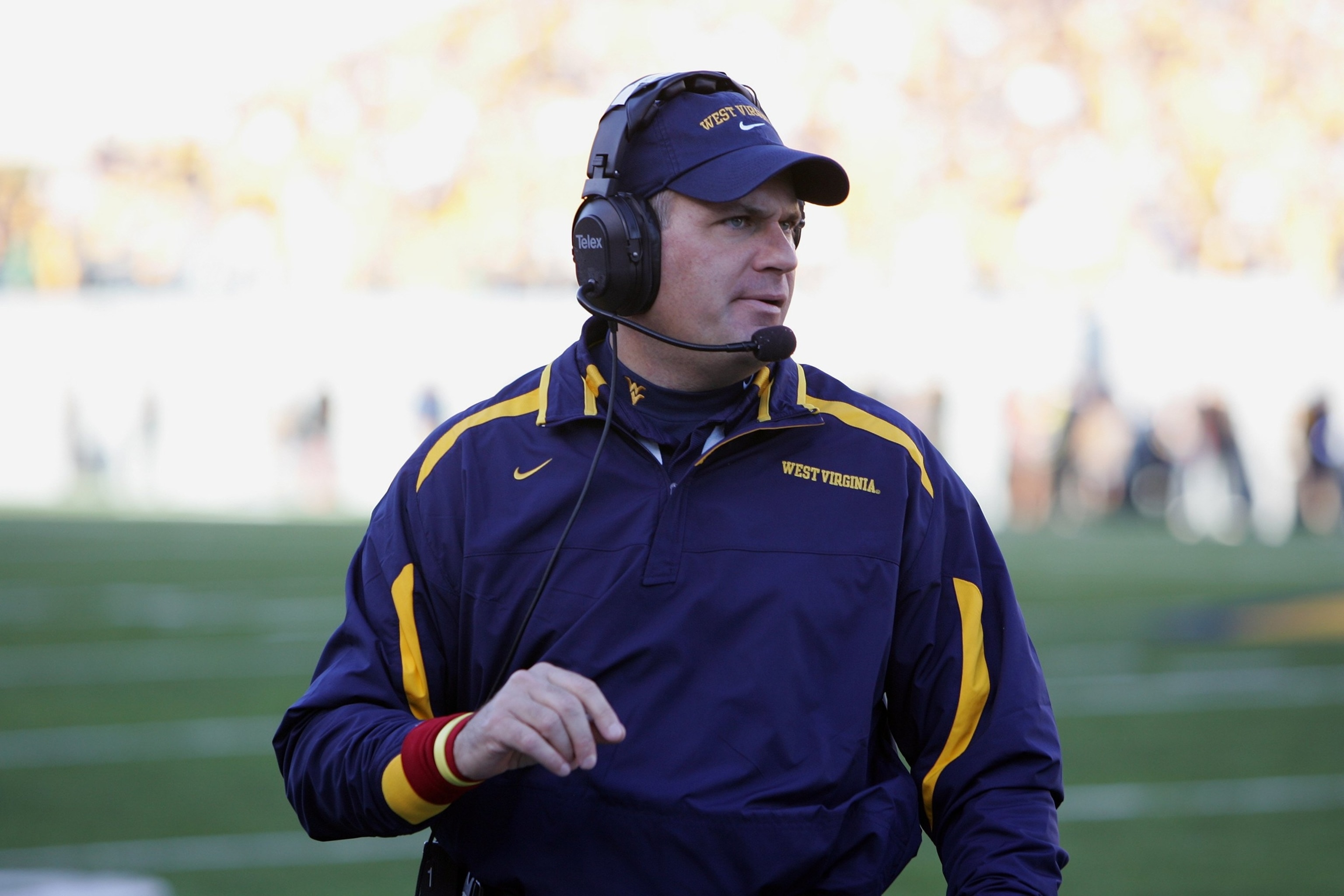 College football coach reviewing approved in-game video on a sideline tablet